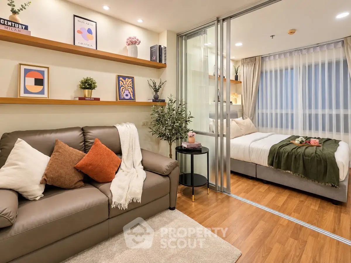 Modern studio apartment with cozy living area and stylish bedroom separated by glass partition.
