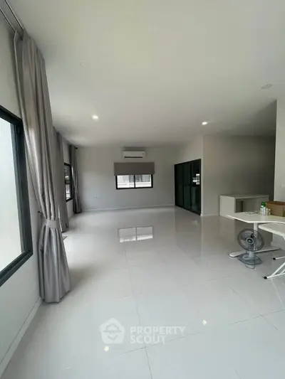 Spacious modern living room with large windows and sleek tile flooring