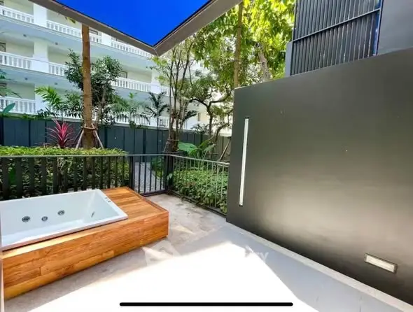 Luxurious garden view with private outdoor jacuzzi in modern apartment complex.