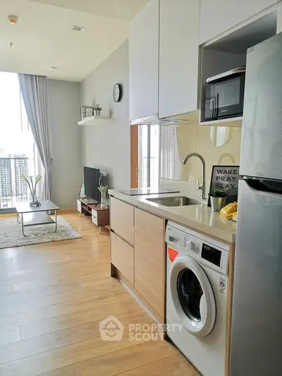 Modern open-plan living room with kitchen, featuring sleek appliances and a cozy balcony view.