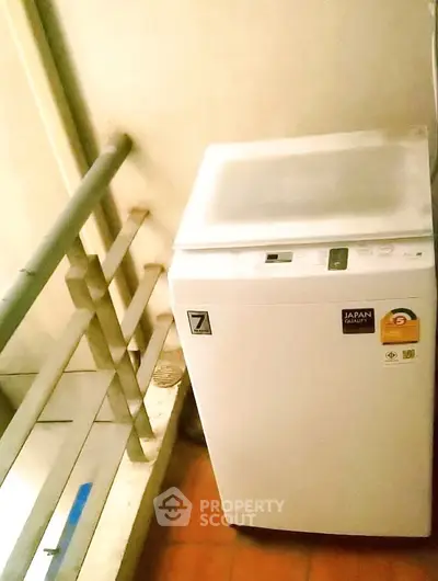 Compact washing machine on a small balcony with railing, ideal for urban apartments.