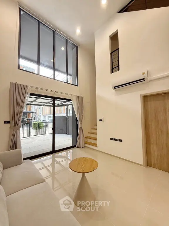Spacious modern living room with high ceiling and large windows in a stylish home.