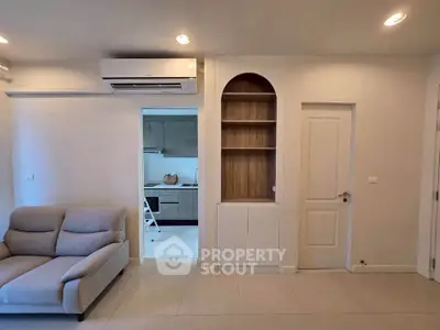 Modern living room with open kitchen layout and stylish built-in shelving.