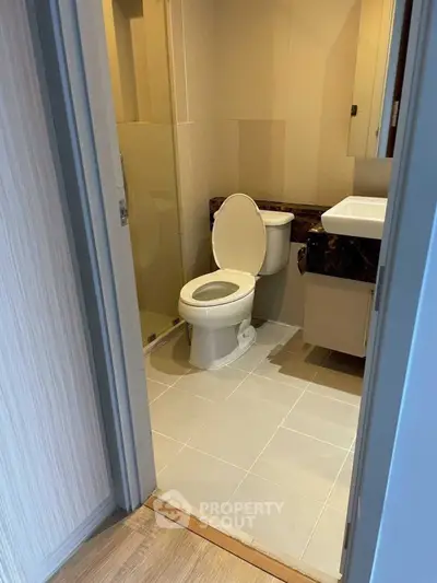 Modern bathroom with sleek design and neutral tones, featuring a toilet and shower area.
