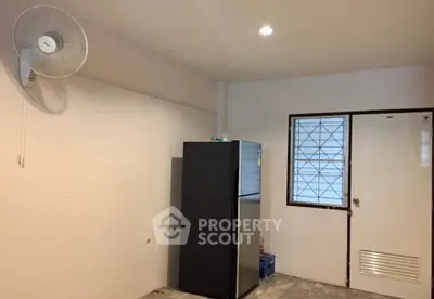 Minimalist kitchen space with refrigerator and wall-mounted fan, ideal for compact living.