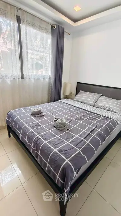 Cozy bedroom with modern decor and ample natural light, featuring a stylish bed and elegant curtains.