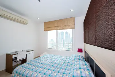 Modern bedroom with city view, featuring stylish decor and ample natural light.