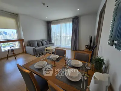 Modern living room with dining area and city view, featuring stylish furniture and natural light.