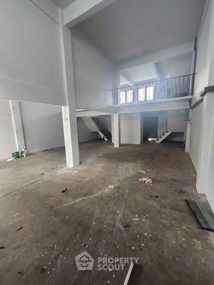 Spacious industrial-style open space with high ceilings and mezzanine, ideal for creative studio or workshop.