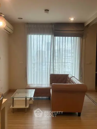 Cozy living room with leather sofa and large window, perfect for relaxation.