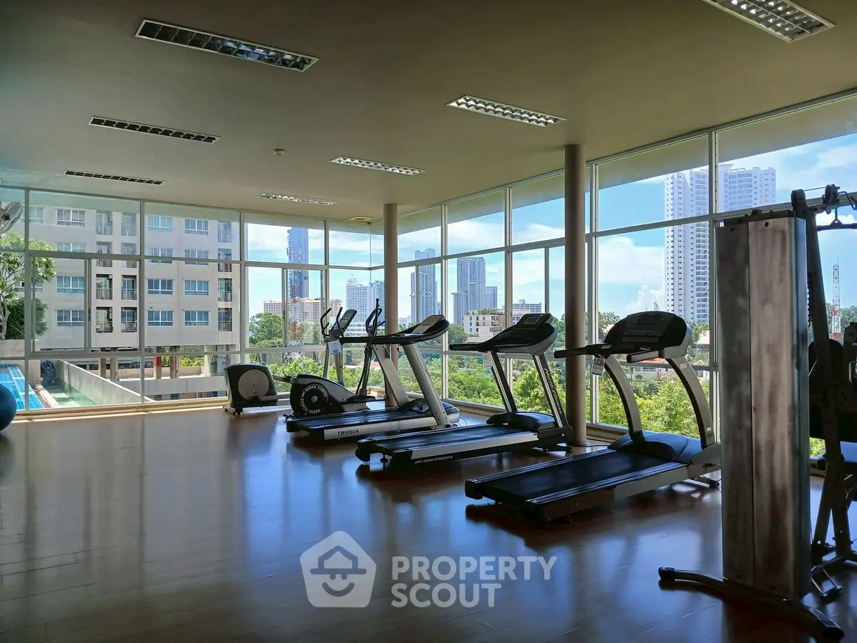 Spacious gym with modern equipment and city view in luxury apartment complex