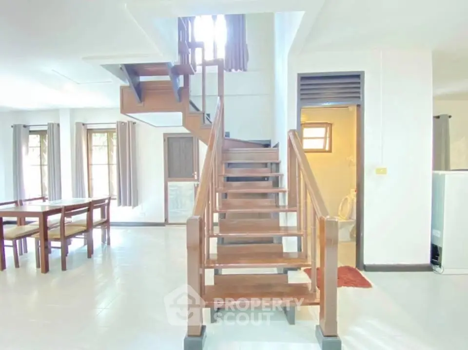 Spacious modern living area with elegant wooden staircase and dining set