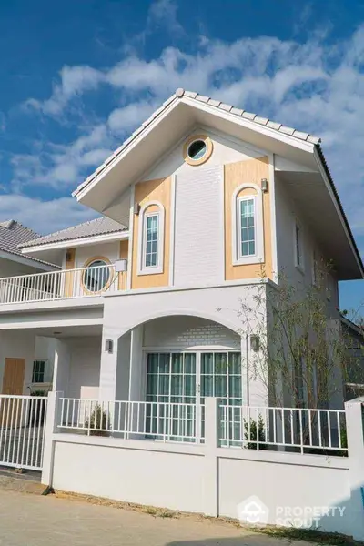 Charming two-story house with modern design and spacious balcony under clear blue sky.