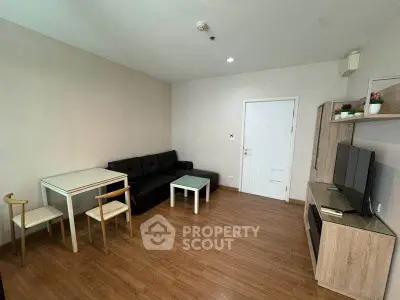 Modern living room with wooden flooring, black sofa, and minimalist furniture in a cozy apartment.
