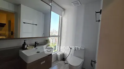 Modern bathroom with city view, featuring sleek fixtures and natural light.