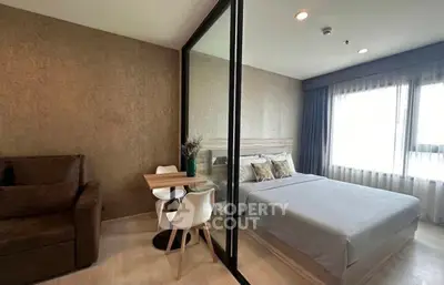 Modern bedroom with glass partition and cozy seating area in stylish apartment.