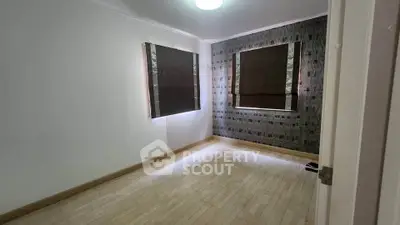 Spacious empty room with wooden flooring and modern window blinds