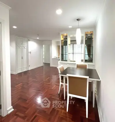 Spacious dining area with elegant parquet flooring and modern lighting in a stylish apartment.