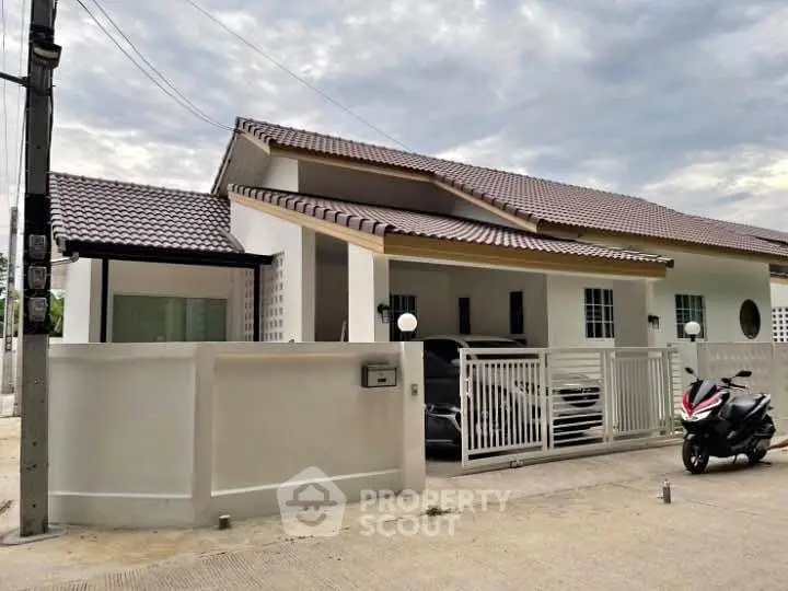 Charming single-story home with tiled roof and gated driveway in a serene neighborhood.