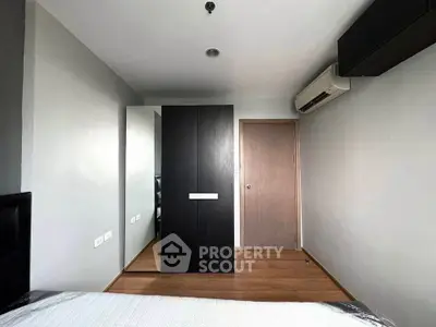 Modern minimalist bedroom with sleek wardrobe and air conditioning unit.