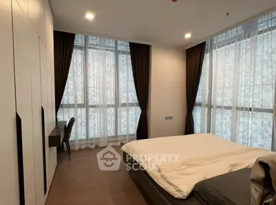 Spacious modern bedroom with large windows and elegant curtains