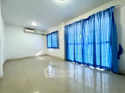 Spacious empty living room with blue curtains and tiled flooring
