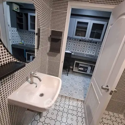 Stylish bathroom with modern sink and geometric tile design, leading to a chic study area.