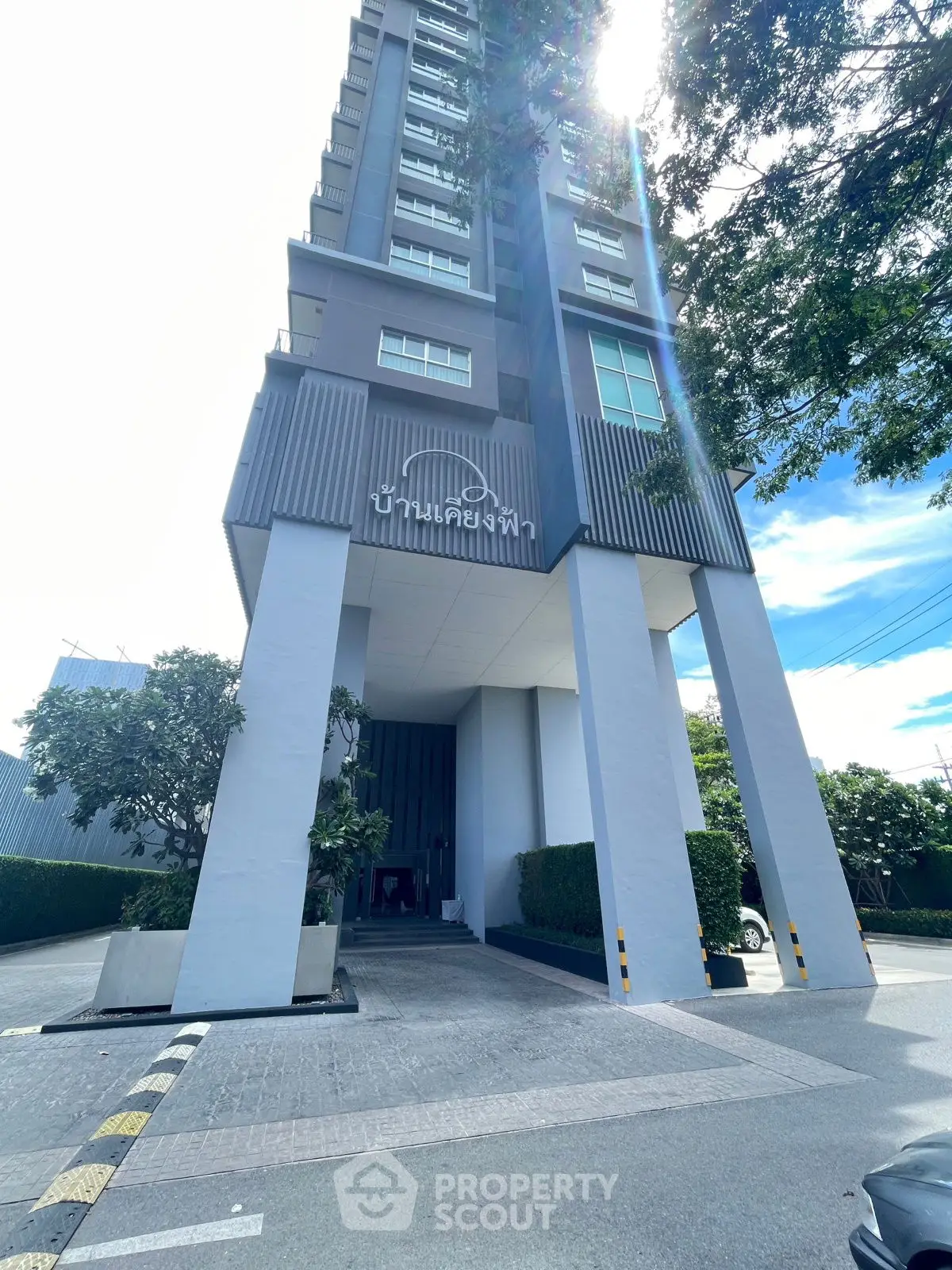 Modern high-rise building entrance with sleek design and lush greenery