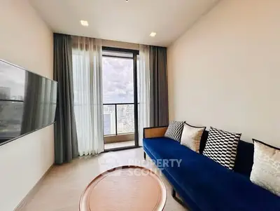 Modern living room with blue sofa and city view from large window.