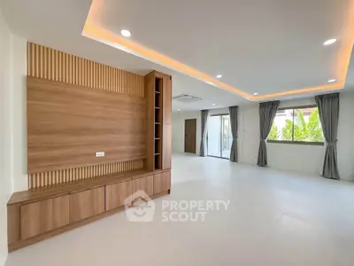 Spacious modern living room with elegant wood paneling and large windows offering natural light.