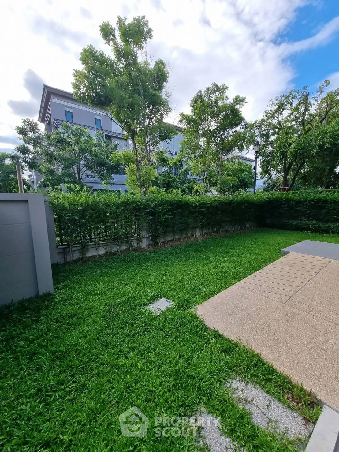 Lush green garden with modern building backdrop, perfect for outdoor relaxation.