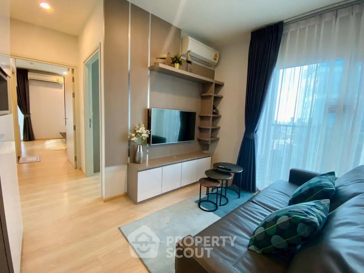 Modern living room with stylish decor and natural light, featuring a cozy sofa and entertainment unit.