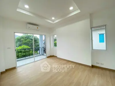 Spacious living room with large windows and balcony access, featuring modern recessed lighting and wood flooring.