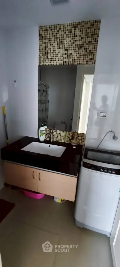 Modern bathroom with washing machine and stylish sink in a contemporary home.