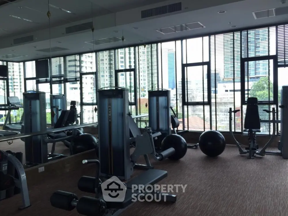 Modern gym with city view and state-of-the-art equipment in luxury building.