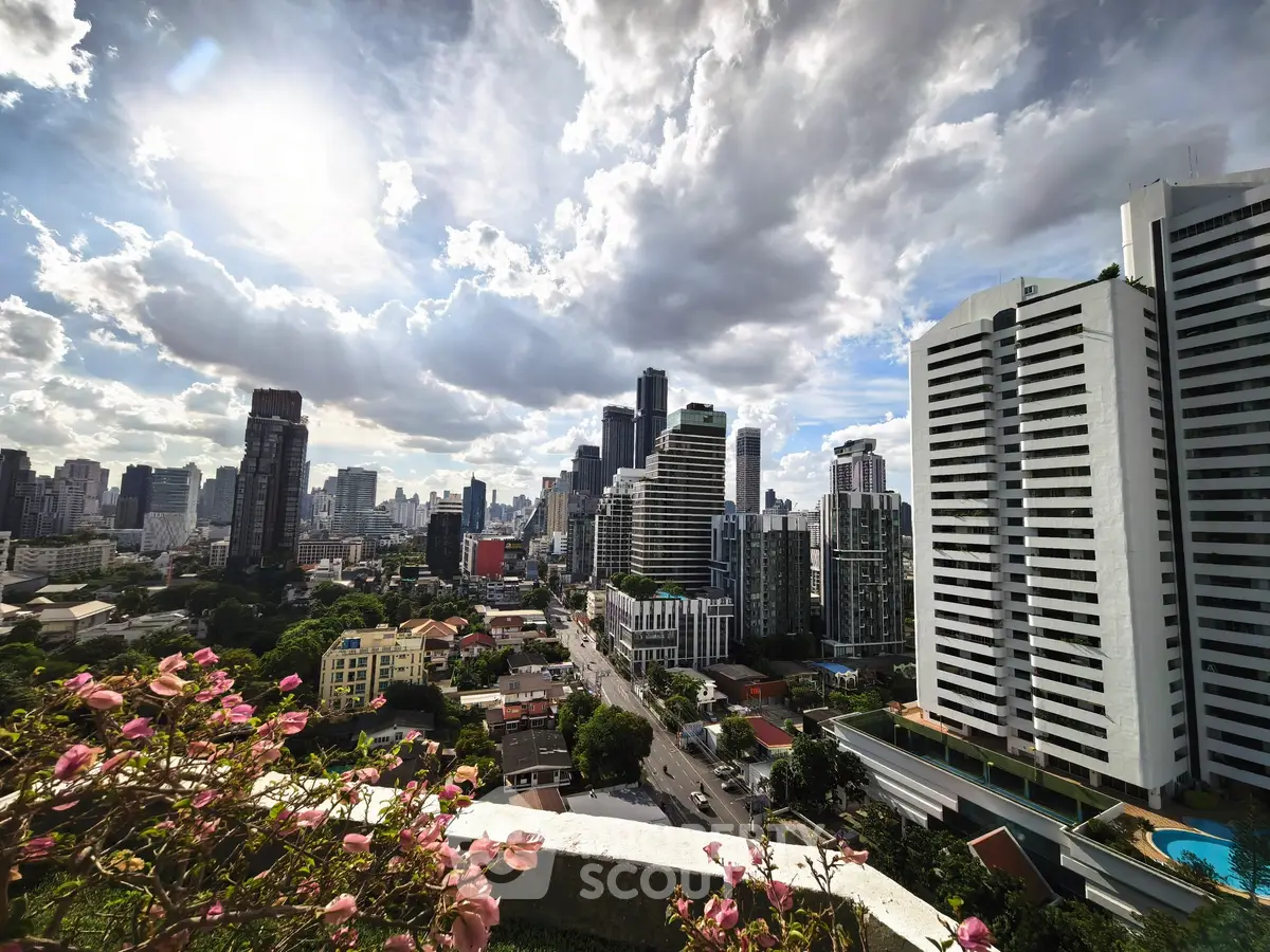 Stunning cityscape view from a high-rise balcony with lush greenery and modern skyscrapers.