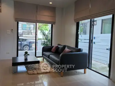 Modern living room with sleek black sofa and large windows