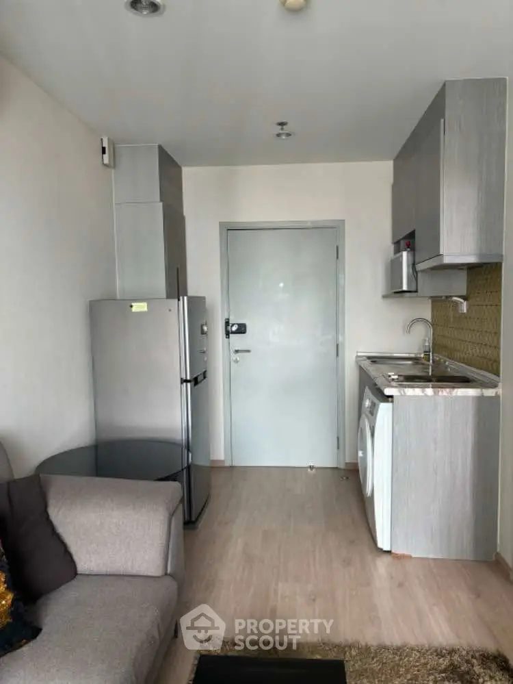 Compact modern apartment with kitchen and living area featuring fridge and washing machine.