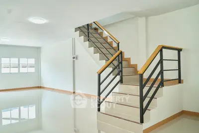 Spacious modern interior with sleek staircase and large windows, perfect for contemporary living.
