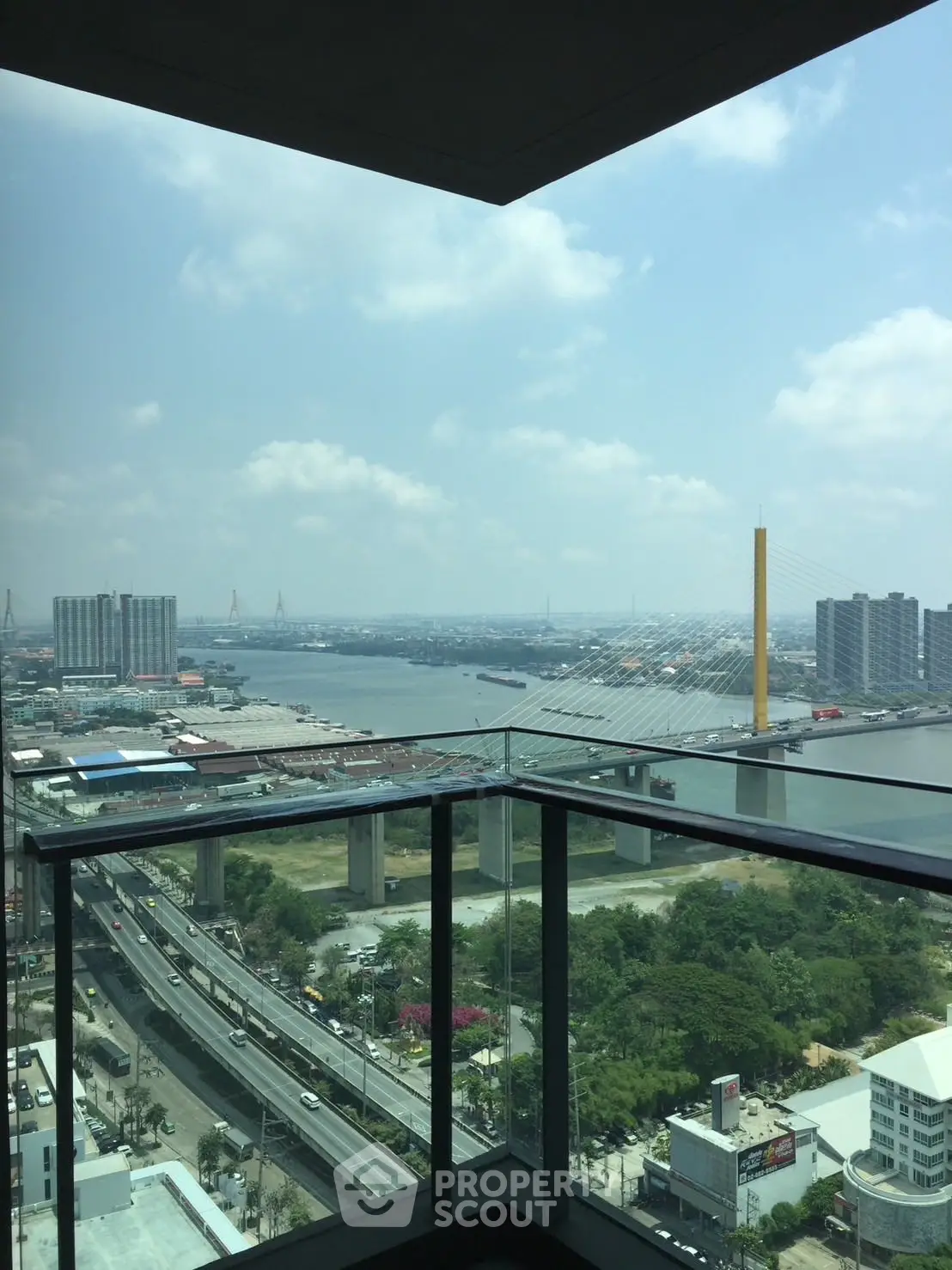 Stunning high-rise balcony view overlooking river and cityscape with iconic bridge.