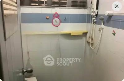 Compact bathroom with shower and wall-mounted water heater in a tiled interior.