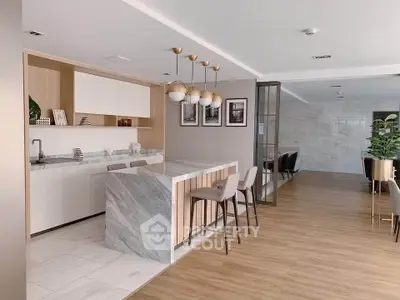 Modern open kitchen with marble island and stylish lighting in a spacious apartment.