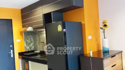 Modern kitchen with vibrant orange walls, sleek black cabinets, and stainless steel appliances.