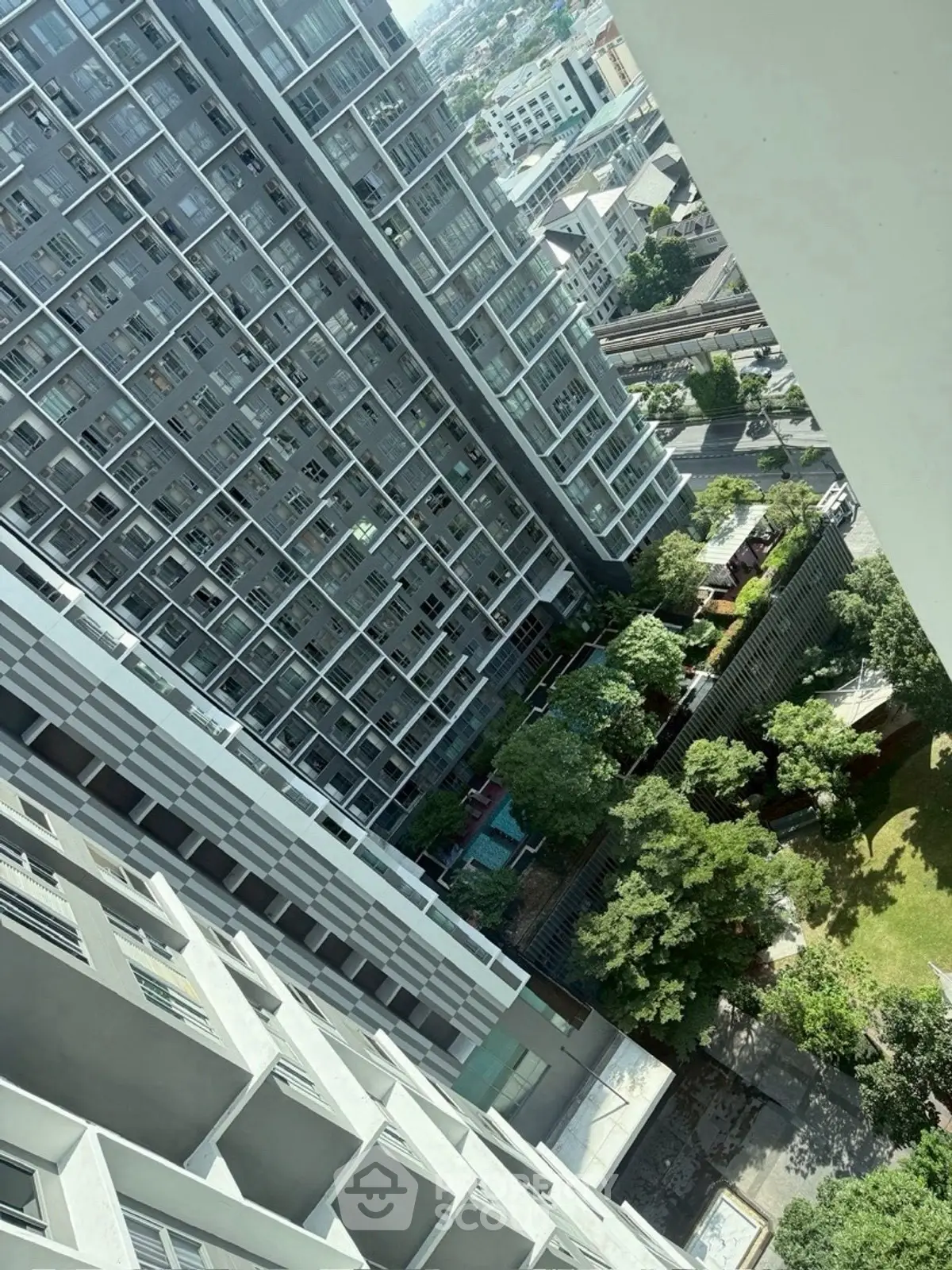 High-rise residential building with lush garden and pool view in urban setting.