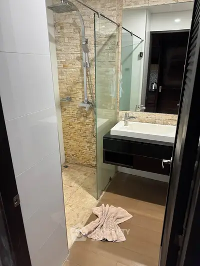 Modern bathroom with stone accent wall and glass shower enclosure