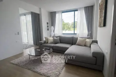 Modern living room with large gray sectional sofa and natural light
