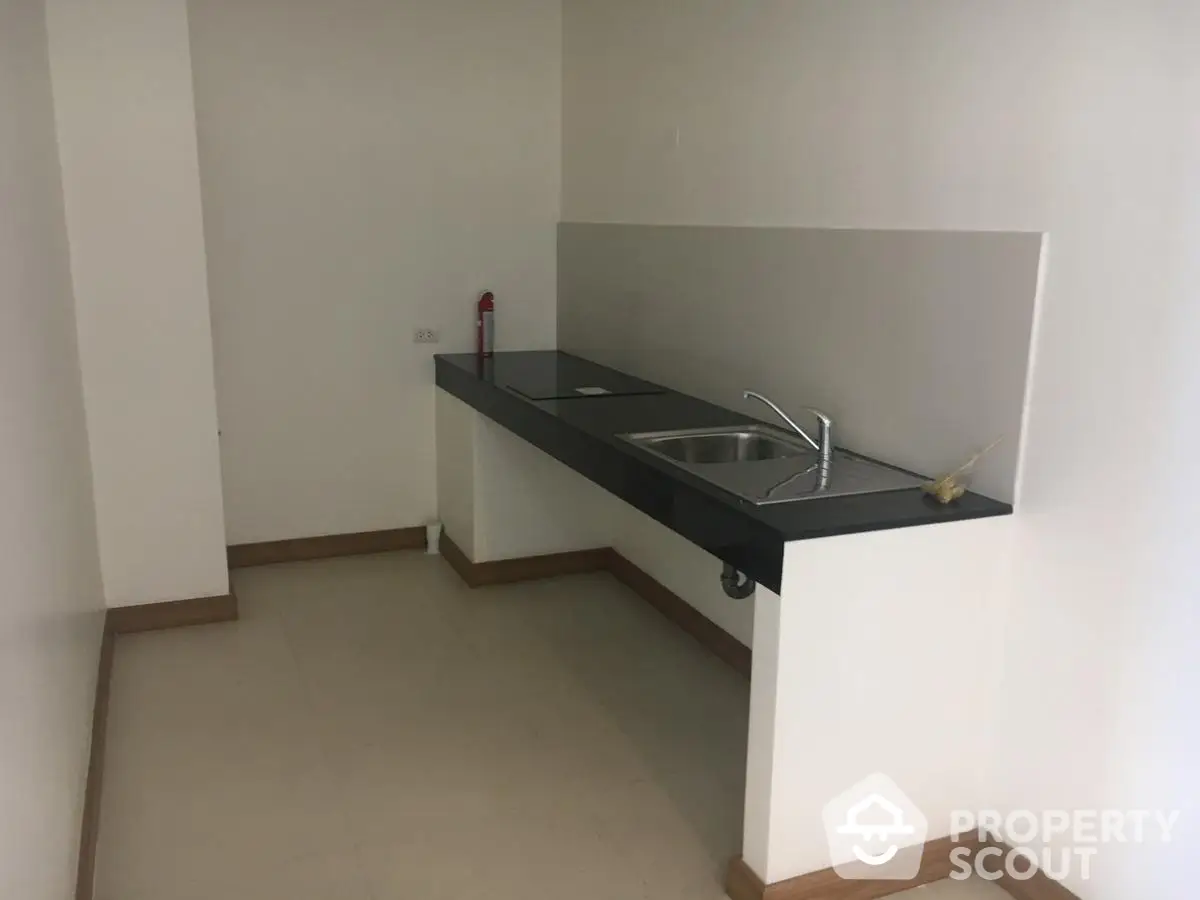 Minimalist kitchen with sleek black countertop and modern sink in a compact space.