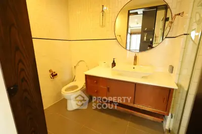 Modern bathroom with stylish vanity and round mirror in elegant apartment.