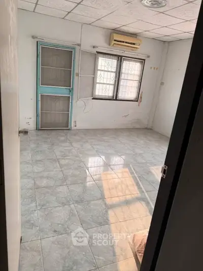 Spacious empty room with tiled floor and large windows, ideal for customization.