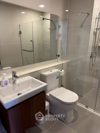 Modern bathroom with sleek fixtures and glass shower enclosure in a contemporary apartment.